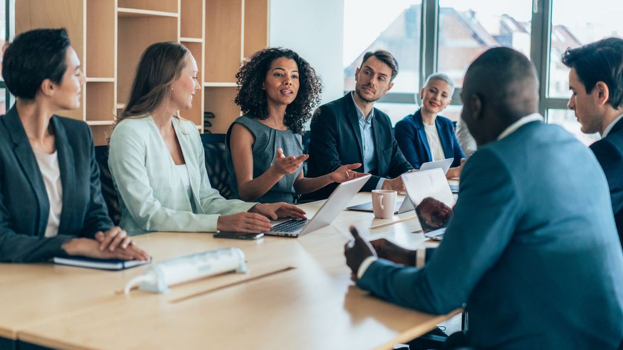 Office men and women around a table discussing strategic alternative investment fund technology