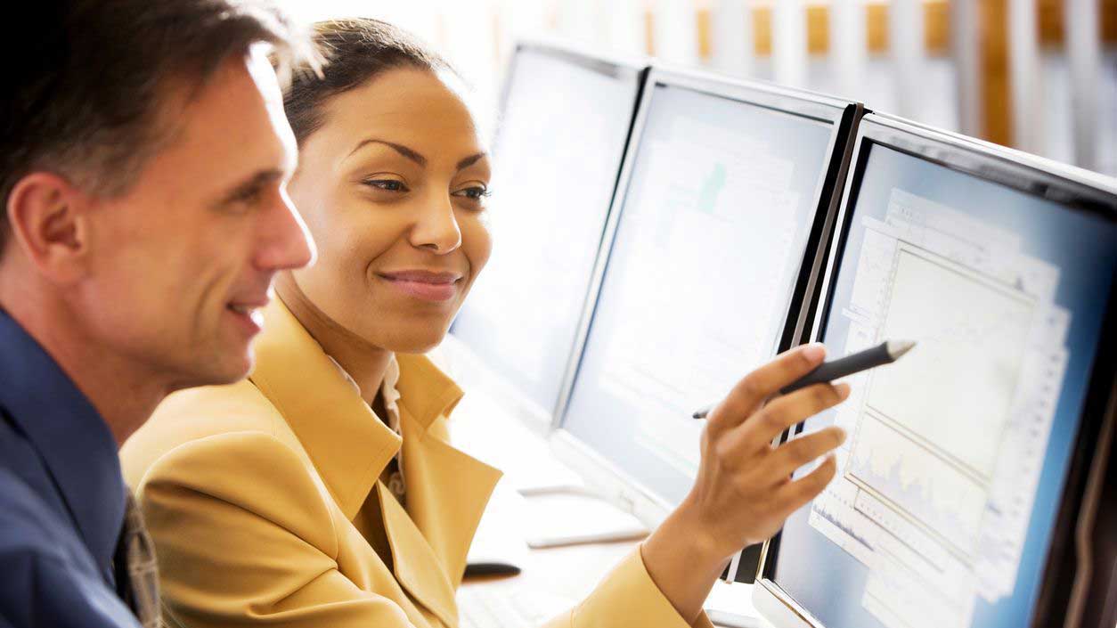 Colleagues at a computer discussing the impact and challenges of moving to ISO 20022 for their business