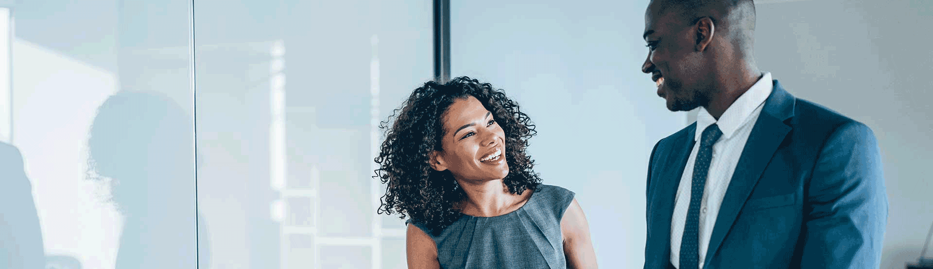 Hombre y mujer de raza negra conversando en una oficina